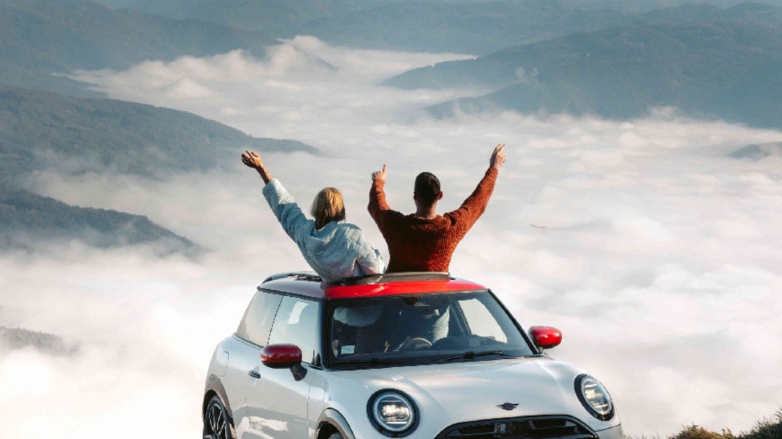 Paar jubelt in MINI mit Blick auf die Berge